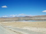 17 Drolung Tso Lake On The Drive To Saga With 6000m Peaks Northeast Of Saga The calm water of the Drolung Tso Lake reflects the hills and 6000m mountains northeast of Saga.